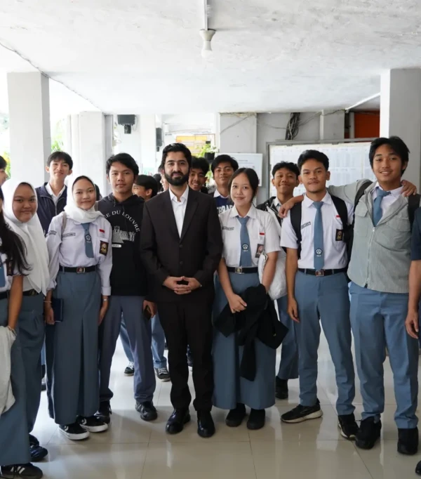Sekelompok siswa dan guru di sekolah, berpose bersama dengan suasana ceria di dalam gedung.